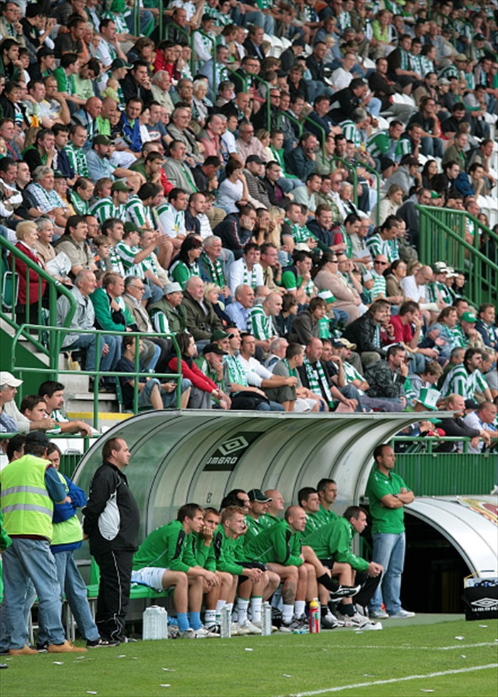 Lavička s tribunou v zádech.